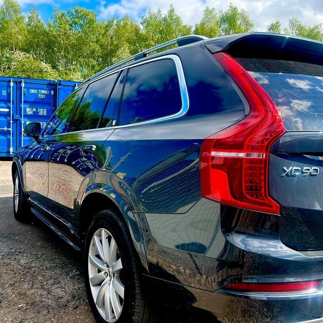 a Volvo car parked near rows of shipping containers