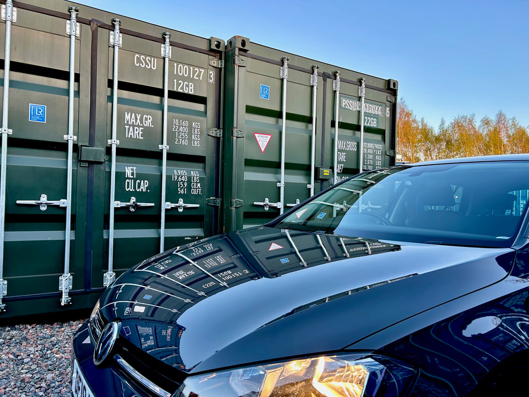 motor car beside two green self storage shipping containers
